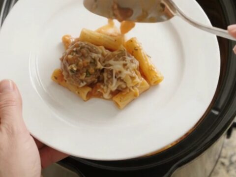 A slow cooker filled with bubbling mozzarella meatball baked ziti