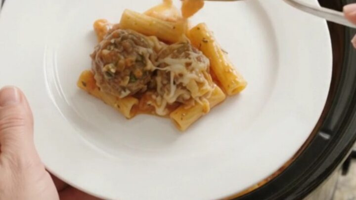 A slow cooker filled with bubbling mozzarella meatball baked ziti
