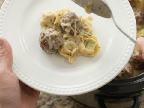 Crockpot filled with creamy Boursin meatball tortellini, topped with melted fontina
