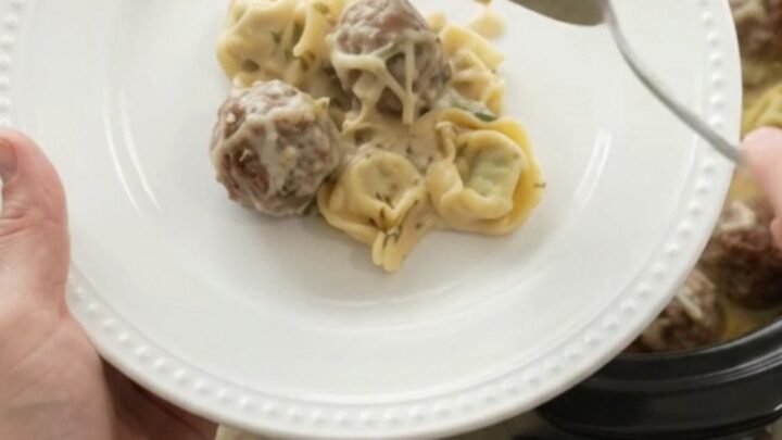 Crockpot filled with creamy Boursin meatball tortellini, topped with melted fontina