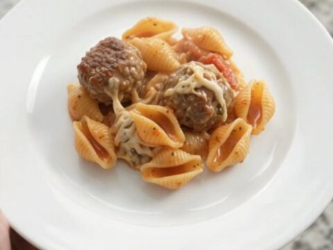 Slow cooker with bubbling mozzarella meatball red pepper shells, cheese stretching from a spoon