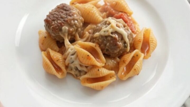 Slow cooker with bubbling mozzarella meatball red pepper shells, cheese stretching from a spoon