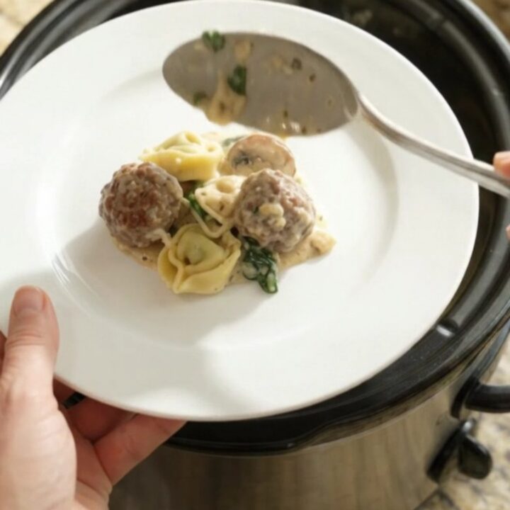 Bubbling Crockpot pasta bake with meatballs, tortellini, mushrooms, and melted provolone cheese