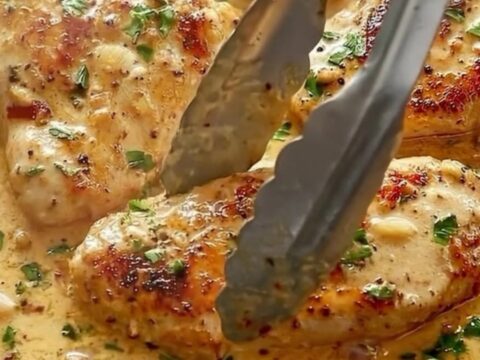 A cast-iron skillet filled with golden-seared chicken cutlets in a creamy garlic sauce with sun-dried tomatoes and parsley.