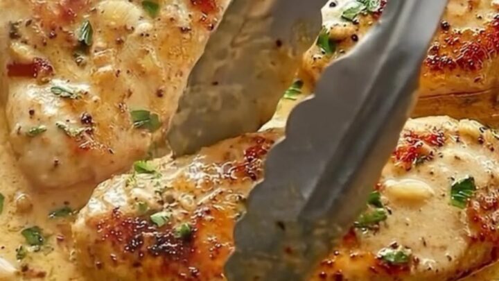 A cast-iron skillet filled with golden-seared chicken cutlets in a creamy garlic sauce with sun-dried tomatoes and parsley.