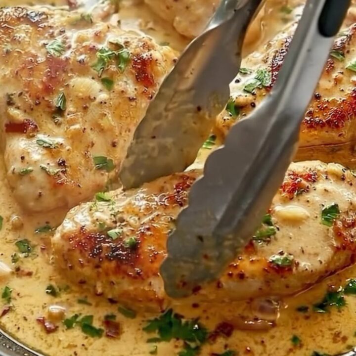 A cast-iron skillet filled with golden-seared chicken cutlets in a creamy garlic sauce with sun-dried tomatoes and parsley.