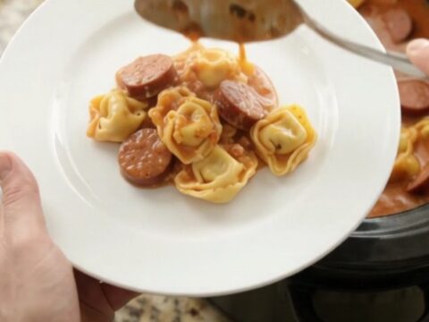 Slow cooker filled with creamy kielbasa tortellini, topped with melted provolone and ricotta.