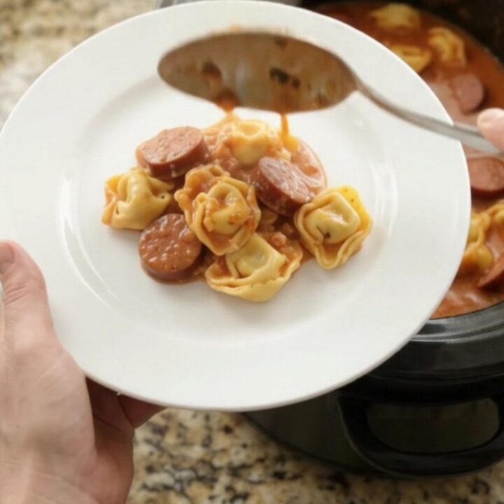 Slow cooker filled with creamy kielbasa tortellini, topped with melted provolone and ricotta.