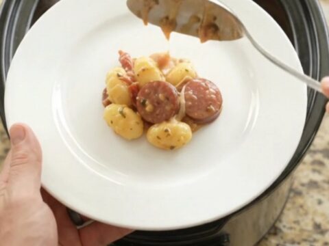 Slow cooker filled with creamy kielbasa and gnocchi, topped with melted mozzarella