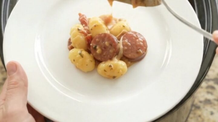 Slow cooker filled with creamy kielbasa and gnocchi, topped with melted mozzarella