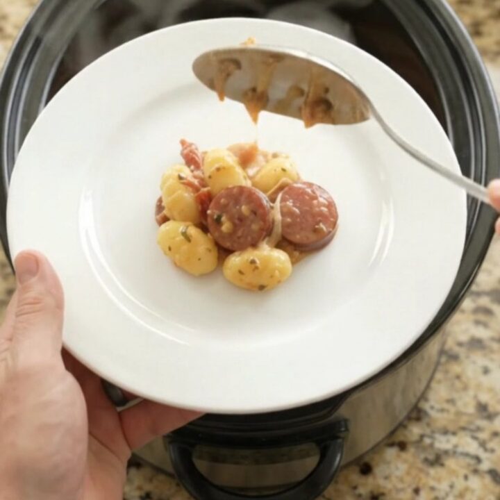Slow cooker filled with creamy kielbasa and gnocchi, topped with melted mozzarella