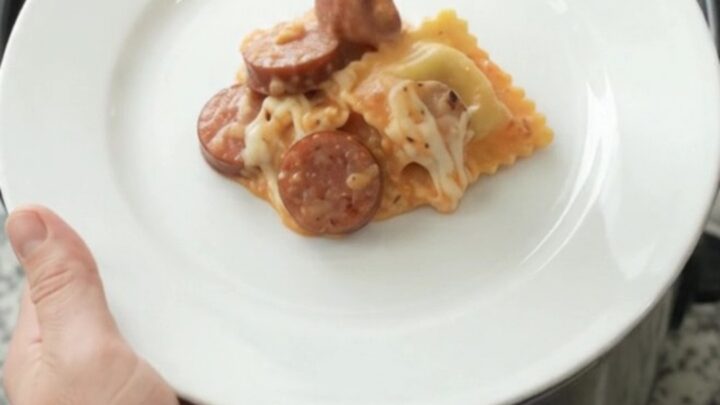 Slow cooker filled with creamy vodka sauce, ravioli, and kielbasa, topped with melted mozzarella.