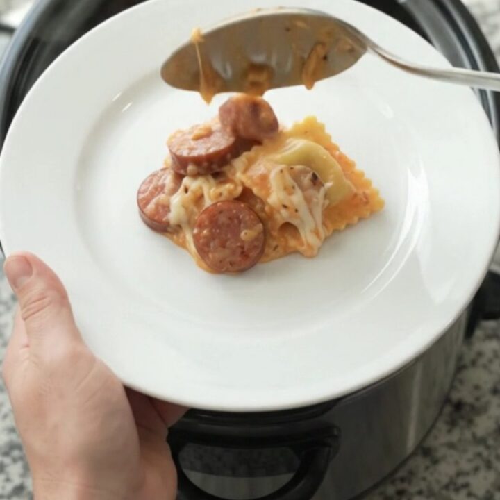Slow cooker filled with creamy vodka sauce, ravioli, and kielbasa, topped with melted mozzarella.