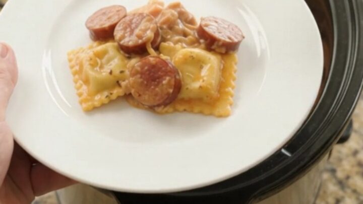 Slow cooker filled with cheesy kielbasa vodka ravioli, bubbling and golden
