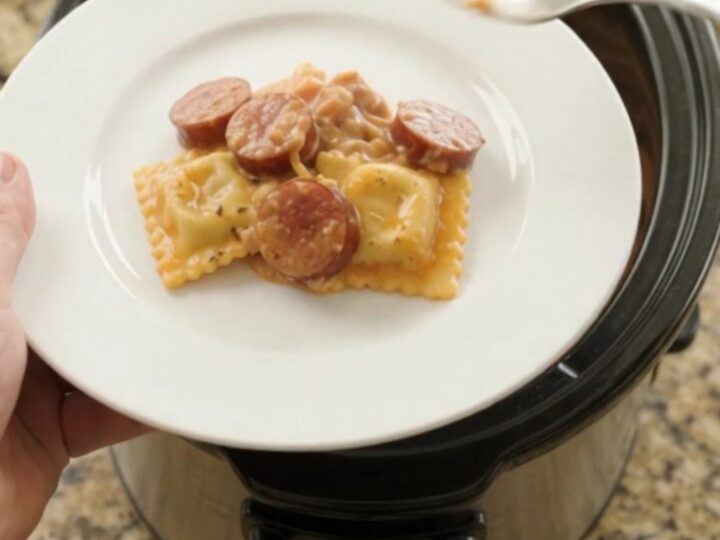 Slow cooker filled with cheesy kielbasa vodka ravioli, bubbling and golden