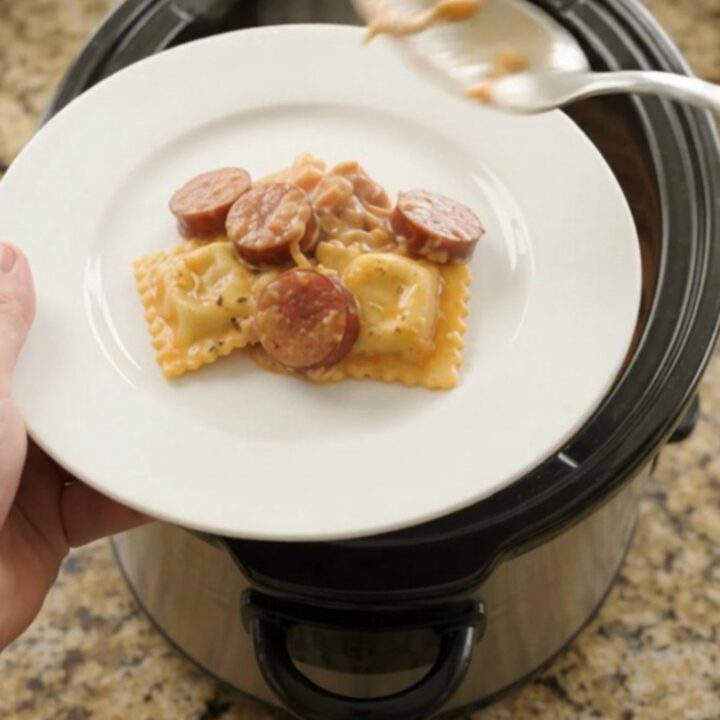 Slow cooker filled with cheesy kielbasa vodka ravioli, bubbling and golden