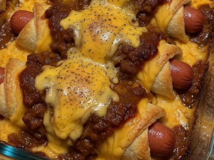 A glass casserole dish filled with six golden-brown chili cheese dog crescent rolls