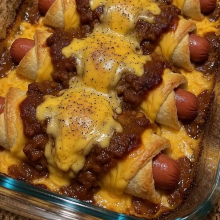A glass casserole dish filled with six golden-brown chili cheese dog crescent rolls