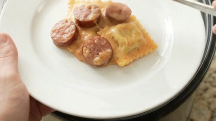 Slow cooker filled with creamy kielbasa vodka ravioli, topped with melted fontina and Boursin cheese.