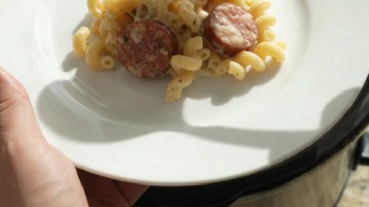 Creamy cavatappi pasta with smoked kielbasa in a slow cooker, topped with melted cheese and Parmesan