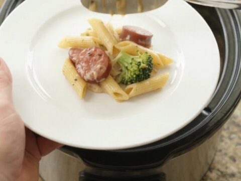 Creamy slow cooker pasta with smoked kielbasa, broccoli, and melted fontina, served in a bowl.