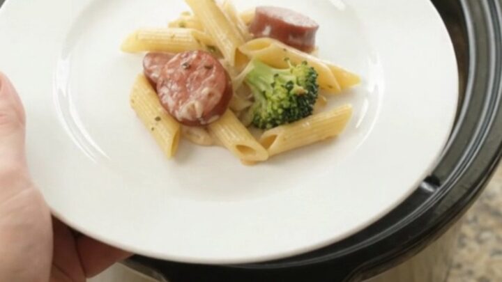 Creamy slow cooker pasta with smoked kielbasa, broccoli, and melted fontina, served in a bowl.