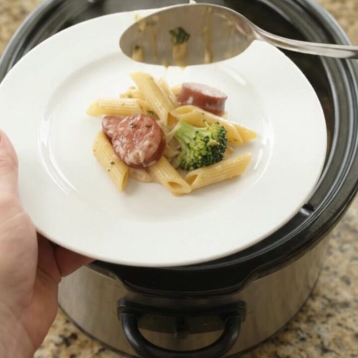 Creamy slow cooker pasta with smoked kielbasa, broccoli, and melted fontina, served in a bowl.