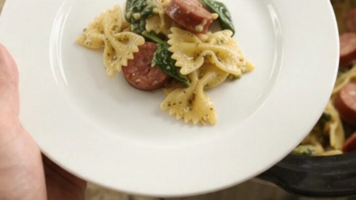 Slow cooker filled with bubbling cheesy pasta, kielbasa, and spinach, topped with melted Parmesan