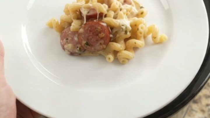 Slow cooker full of creamy cavatappi with kielbasa, melted cheese, and steam rising