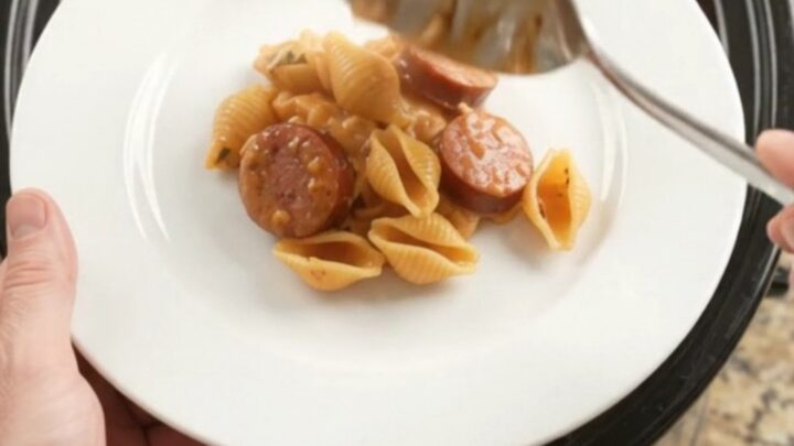 Bubbling Crockpot casserole with smoked kielbasa, pasta shells, and melted provolone cheese