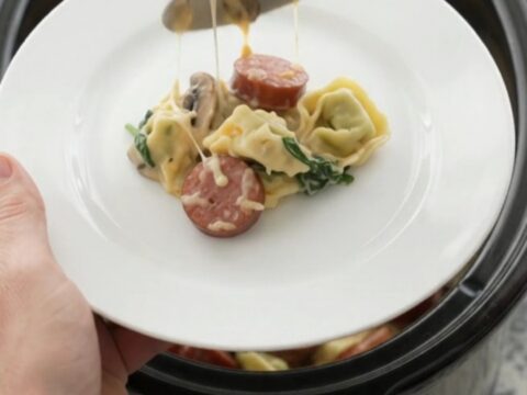 Slow cooker filled with creamy kielbasa tortellini, topped with melted cheese and golden crust.