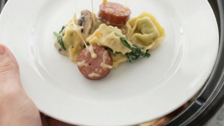 Slow cooker filled with creamy kielbasa tortellini, topped with melted cheese and golden crust.