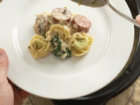 Crockpot full of creamy kielbasa and tortellini with melted provolone
