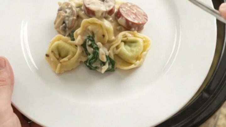 Crockpot full of creamy kielbasa and tortellini with melted provolone