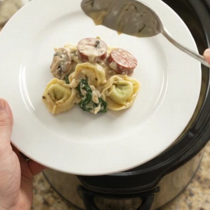 Crockpot full of creamy kielbasa and tortellini with melted provolone