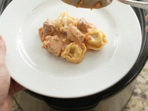 Slow cooker filled with creamy chicken marinara tortellini topped with melted mozzarella