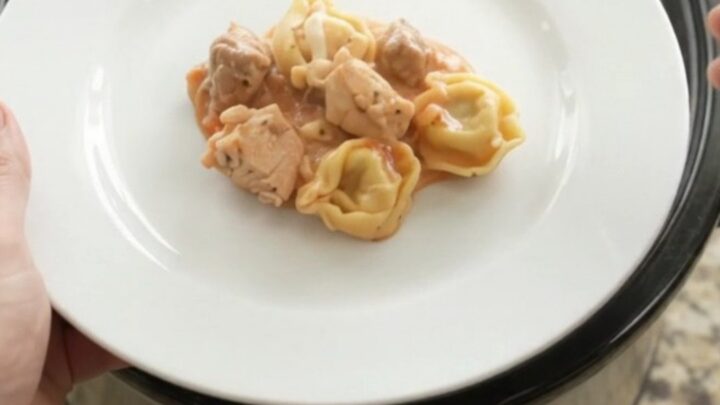 Slow cooker filled with creamy chicken marinara tortellini topped with melted mozzarella