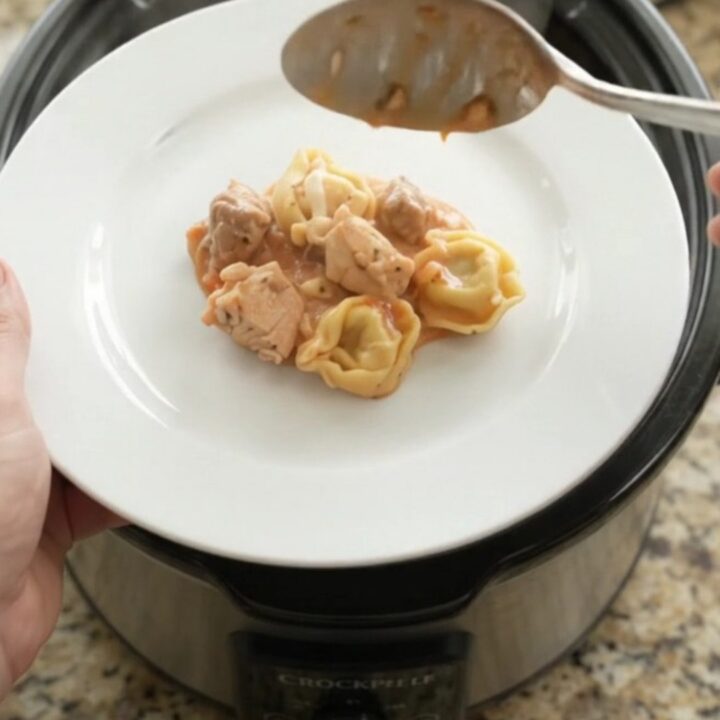 Slow cooker filled with creamy chicken marinara tortellini topped with melted mozzarella