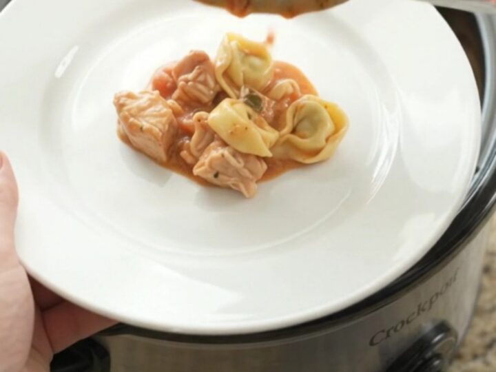 Slow cooker chicken marinara tortellini with melted cheese and a spoonful lifting a cheesy bite.
