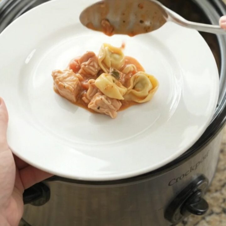 Slow cooker chicken marinara tortellini with melted cheese and a spoonful lifting a cheesy bite.