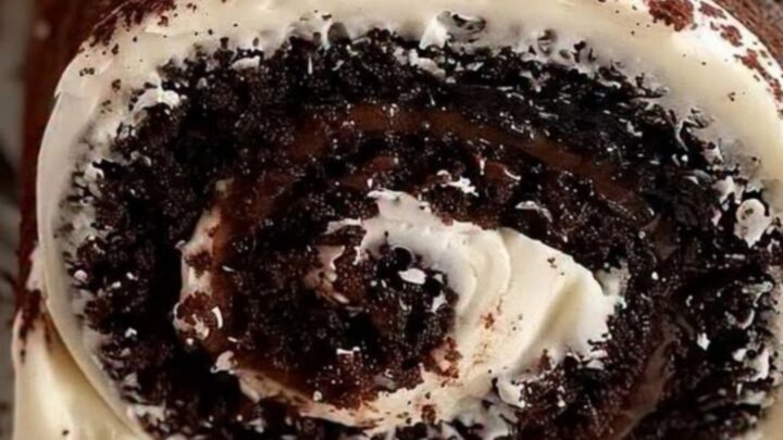 A perfectly sliced chocolate Swiss roll on a white tray, showing clear white cream and fudge swirls.