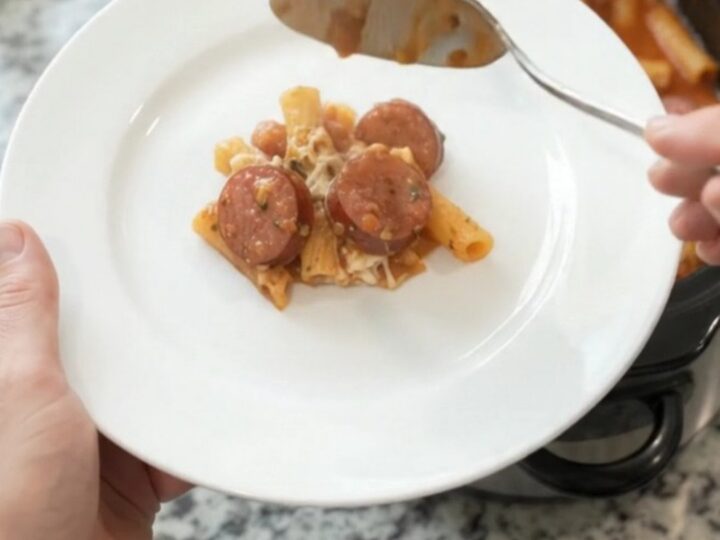 A bubbling Crockpot full of Provolone Kielbasa Baked Ziti, with melted cheese and sausage coins visible.