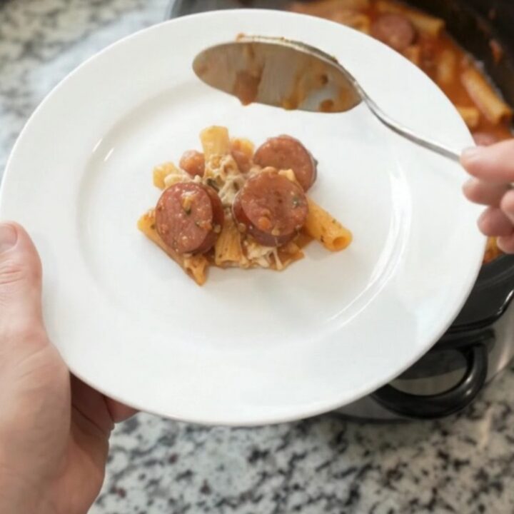 A bubbling Crockpot full of Provolone Kielbasa Baked Ziti, with melted cheese and sausage coins visible.