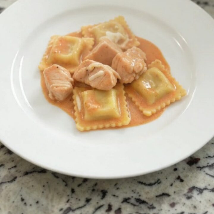 Slow cooker filled with creamy chicken vodka ravioli topped with melted mozzarella.