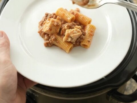 Slow cooker full of creamy chicken rigatoni with melted mozzarella and tomato sauce.