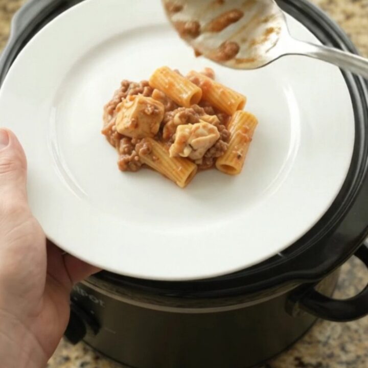 Slow cooker full of creamy chicken rigatoni with melted mozzarella and tomato sauce.