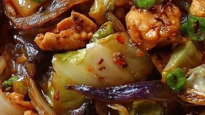 A white bowl filled with glossy, seared chicken and charred cabbage, garnished with fresh chopped scallions.