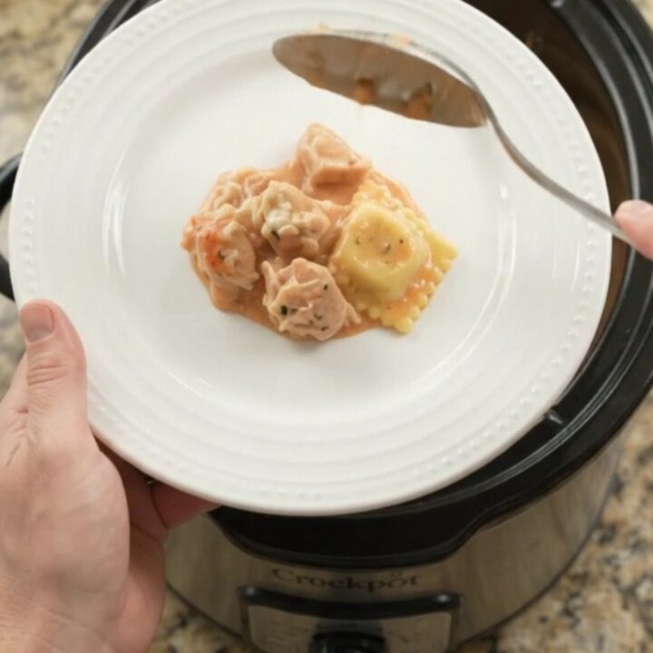 Bubbling slow cooker full of chicken vodka ravioli with melted provolone and ricotta