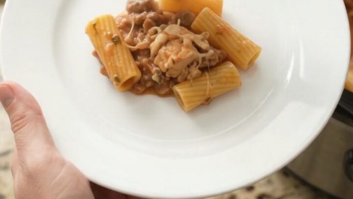 Slow cooker filled with creamy chicken rigatoni, topped with melted fontina and herbs.
