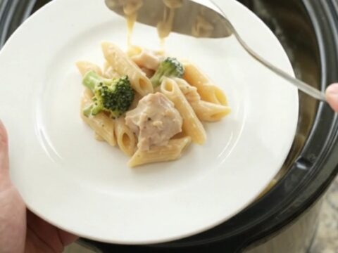 Creamy Crockpot Chicken Alfredo Penne with melted cheese and broccoli in a slow cooker
